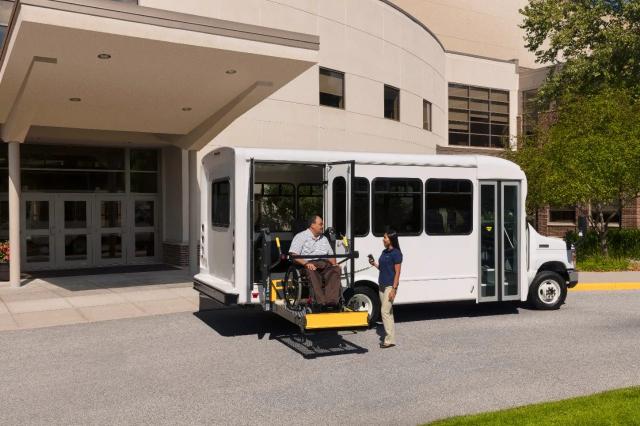 Shuttle bus with rear wheelchair lift at a senior living entrance