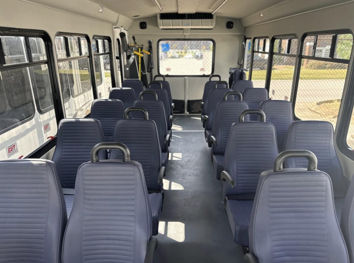 Rear platform wheelchair lift inside a shuttle bus with seats flipped up